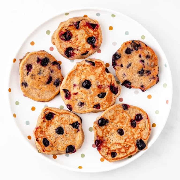 A plate with six mini oatmeal blueberry banana pancakes.