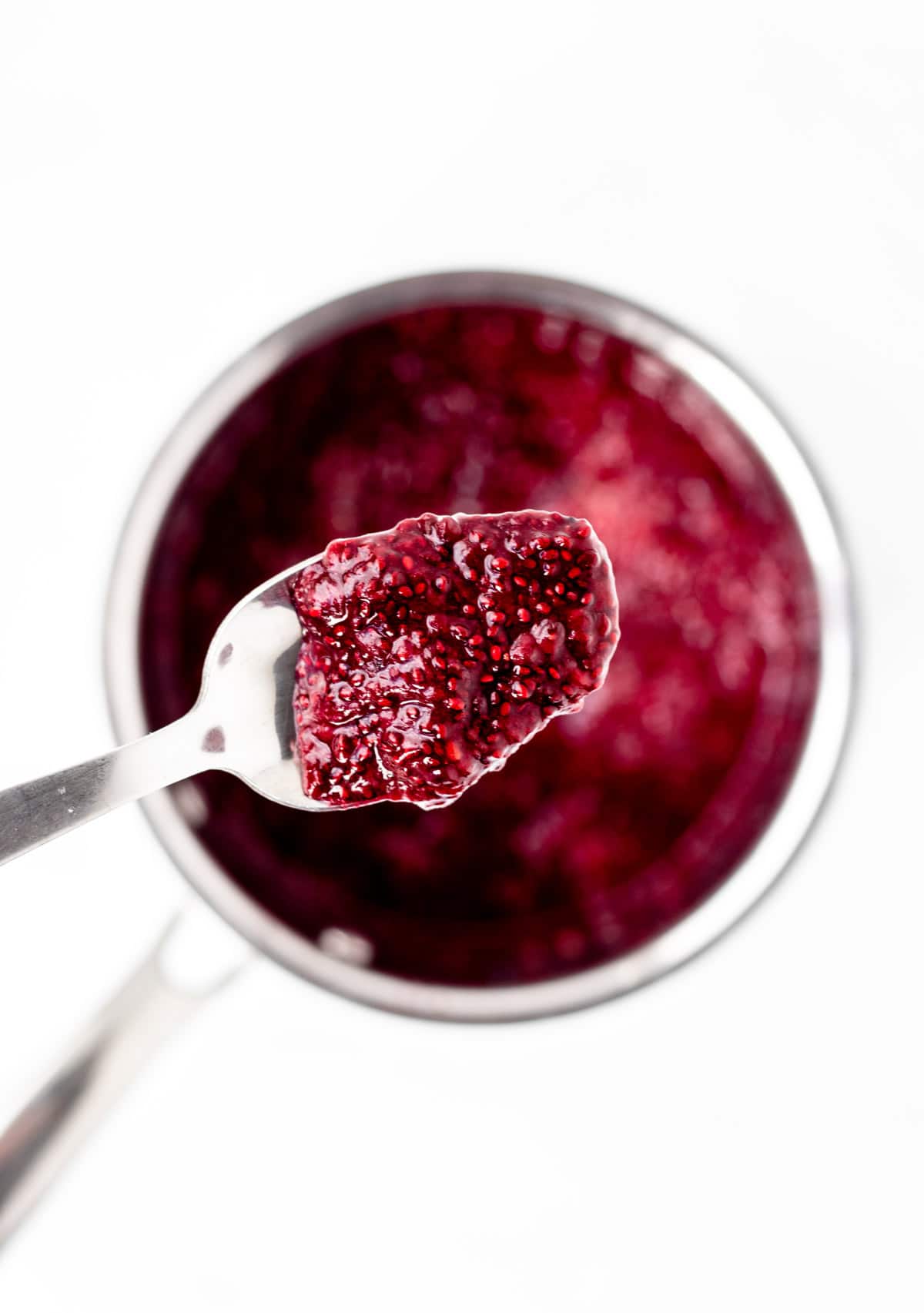 A spoon holding up some berry chia jam.