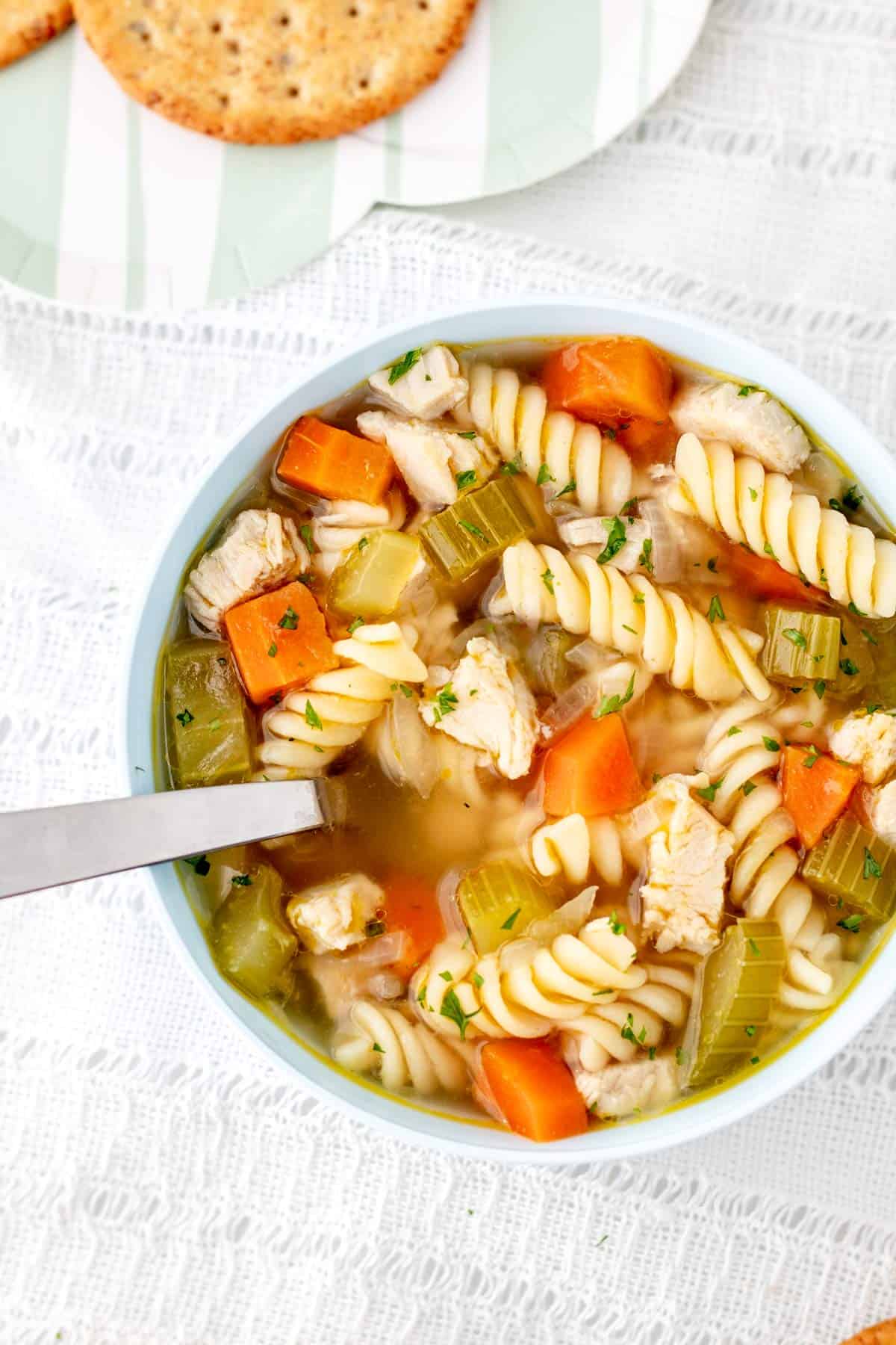 Chicken noodle soup for babies in a white bowl with a spoon.