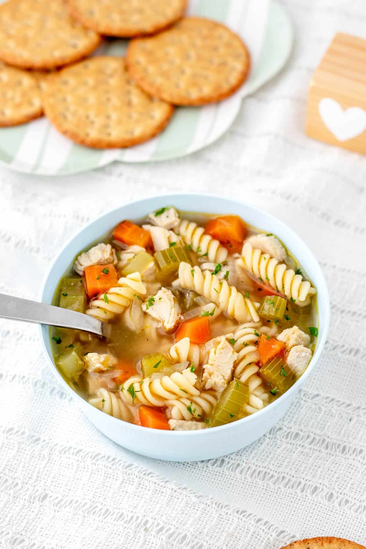 Chicken noodle soup for babies in a white bowl with a spoon.