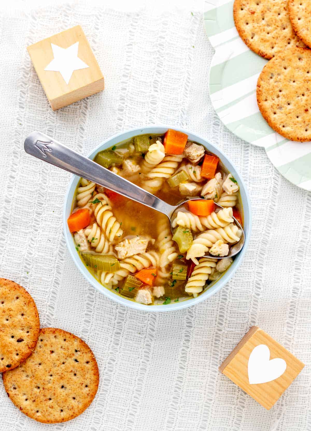 Chicken noodle soup for babies in a blue bowl with a spoon.