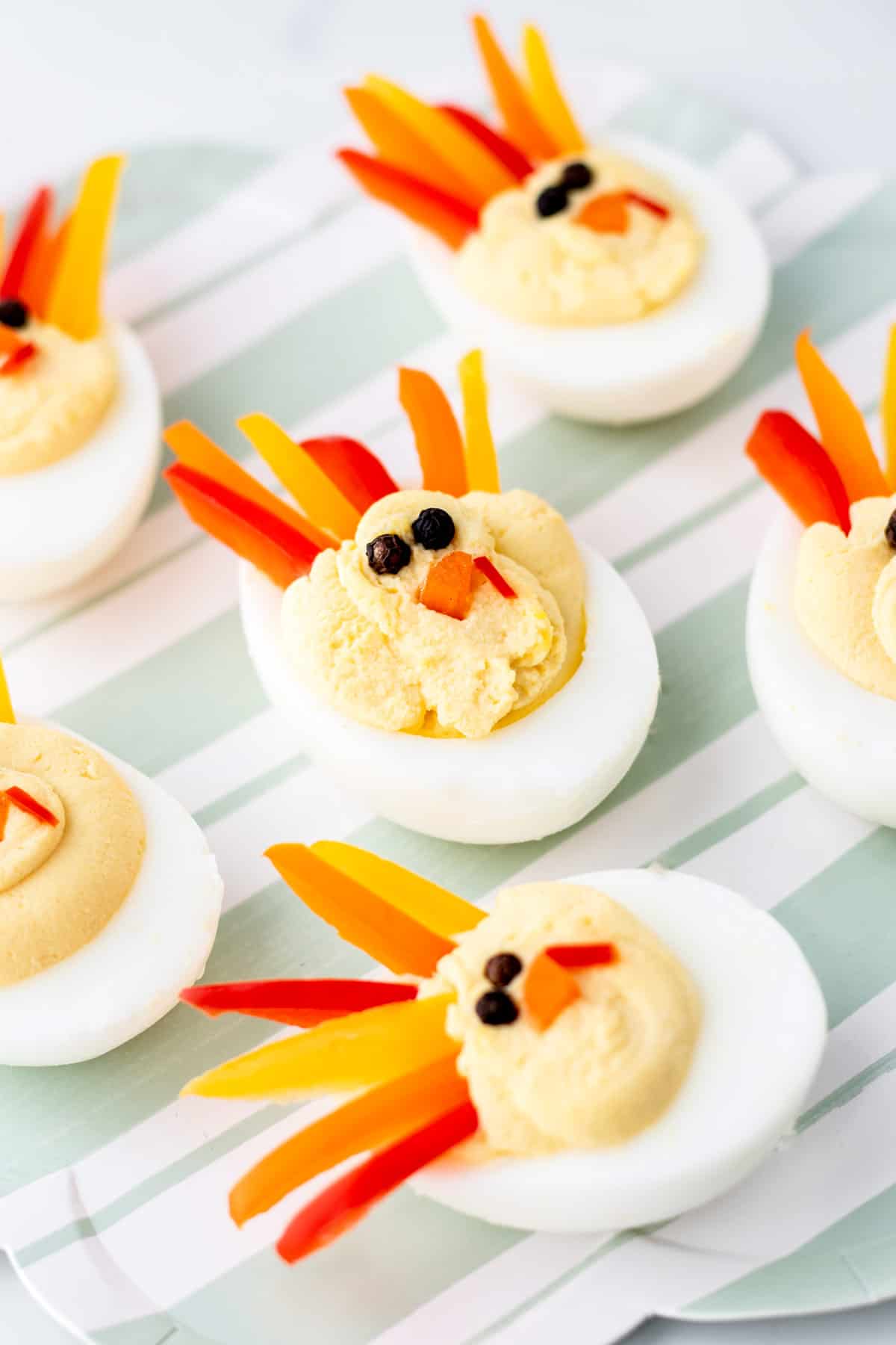 Turkey shaped deviled eggs on a striped green plate.