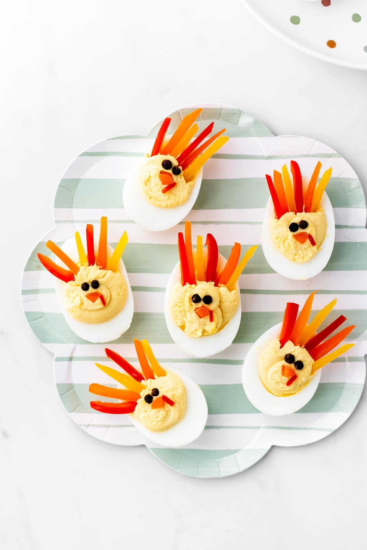 A striped plate with six turkey deviled eggs for Thanksgiving.