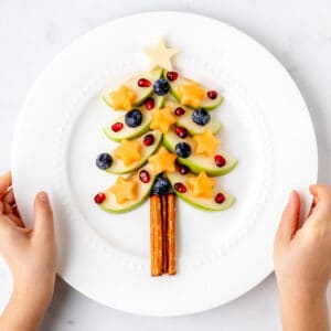 A decorated apple Christmas tree on a white plate.