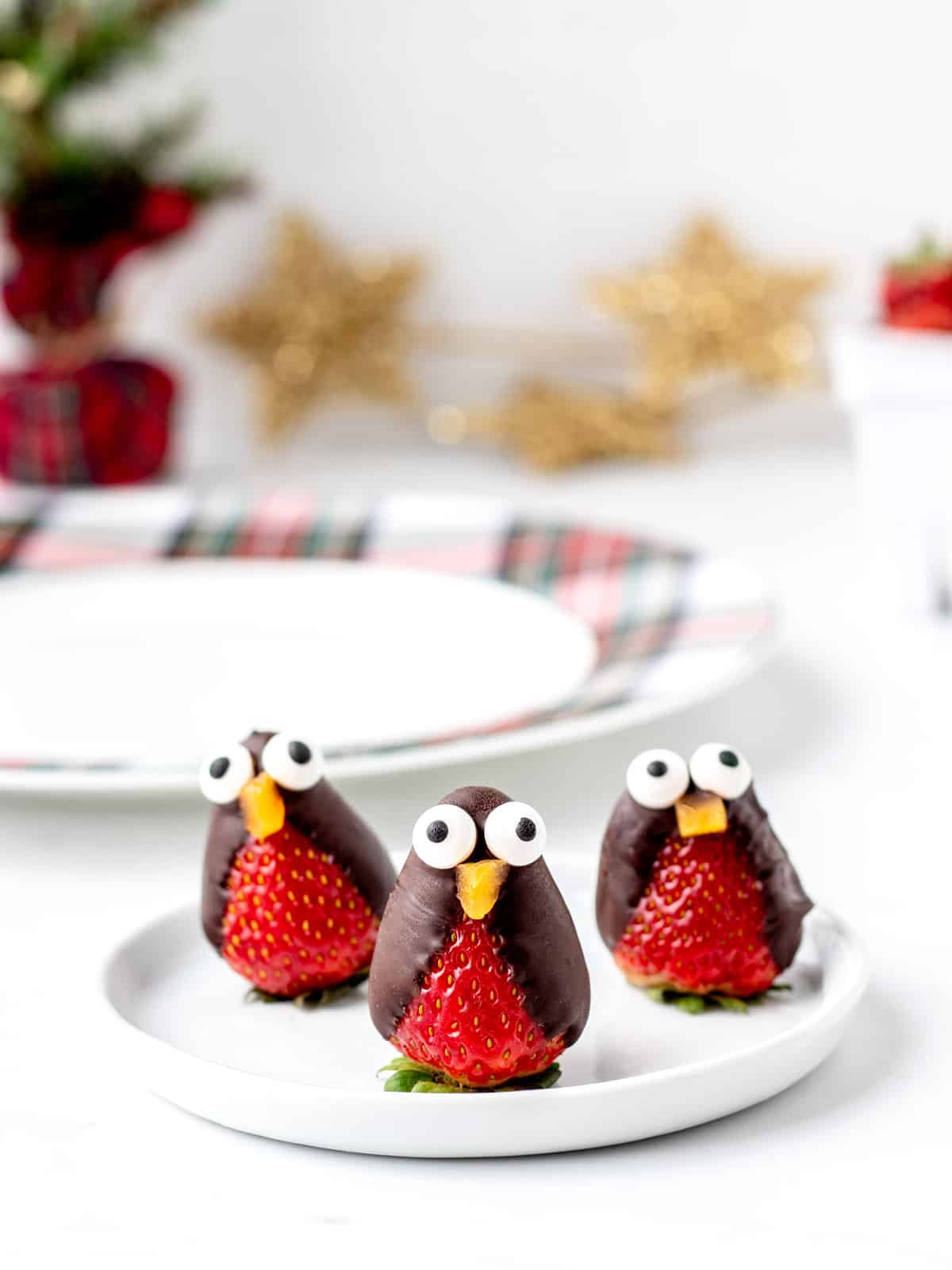Three strawberry penguins on a white plate.
