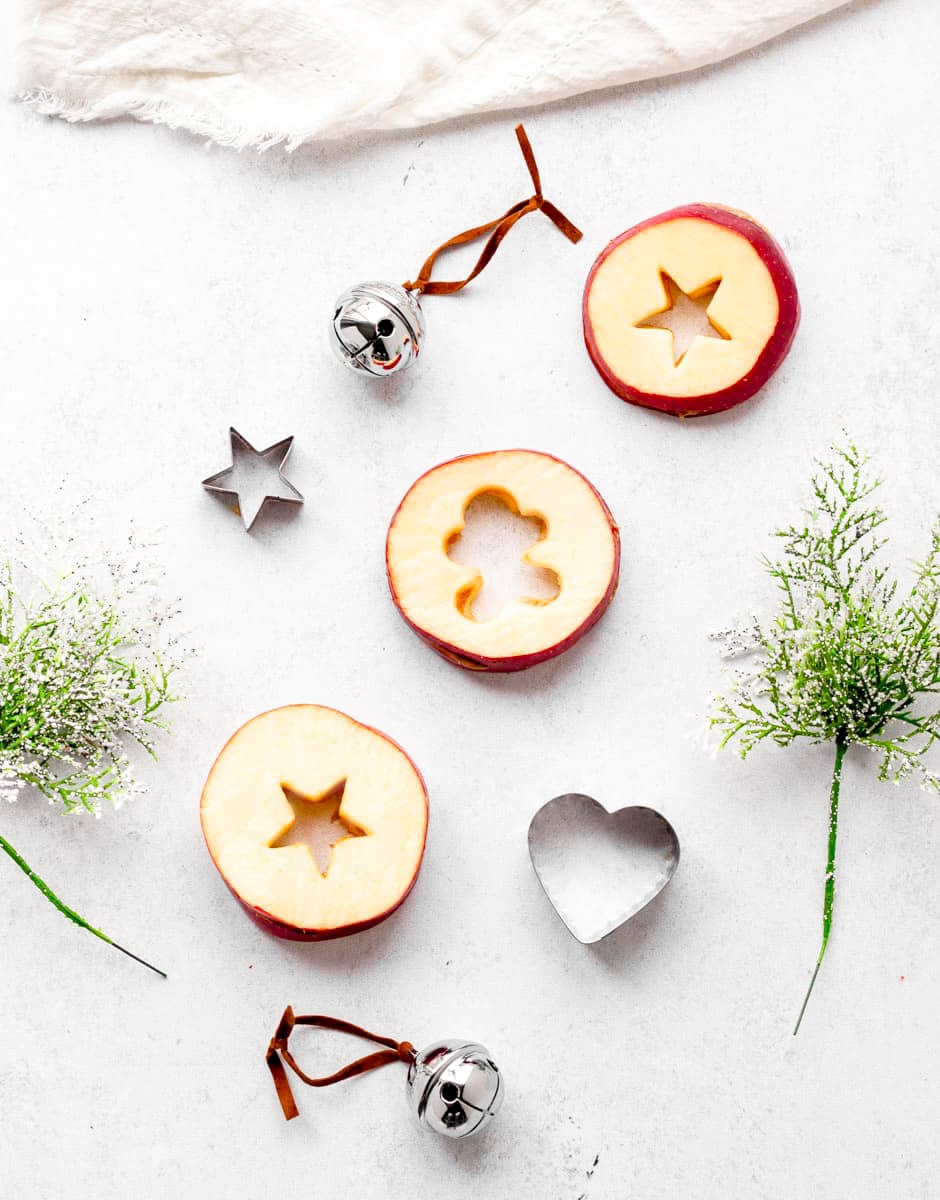 Three apple slices with a stars and a gingerbread man cut out with cookie cutters.