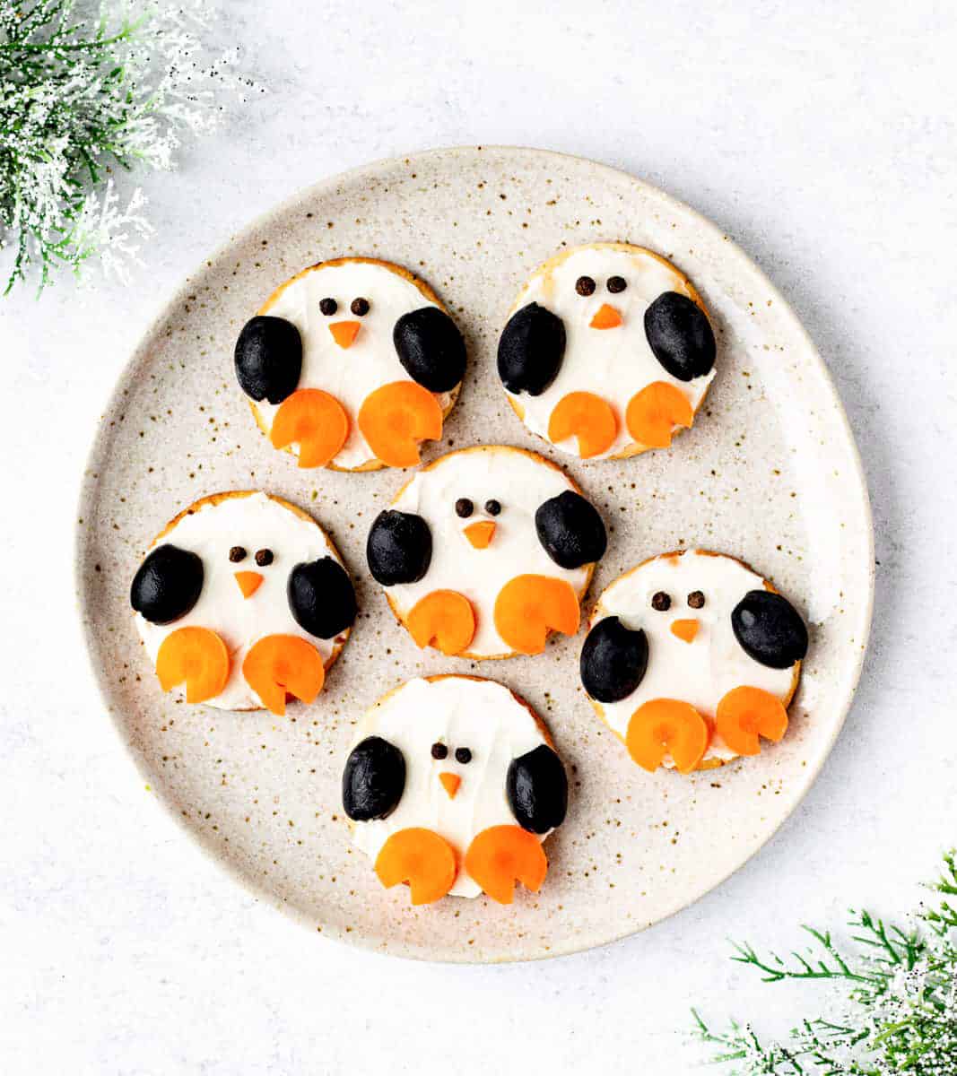 A birds-eye view of 6 penguin crackers on a round, circular plate.