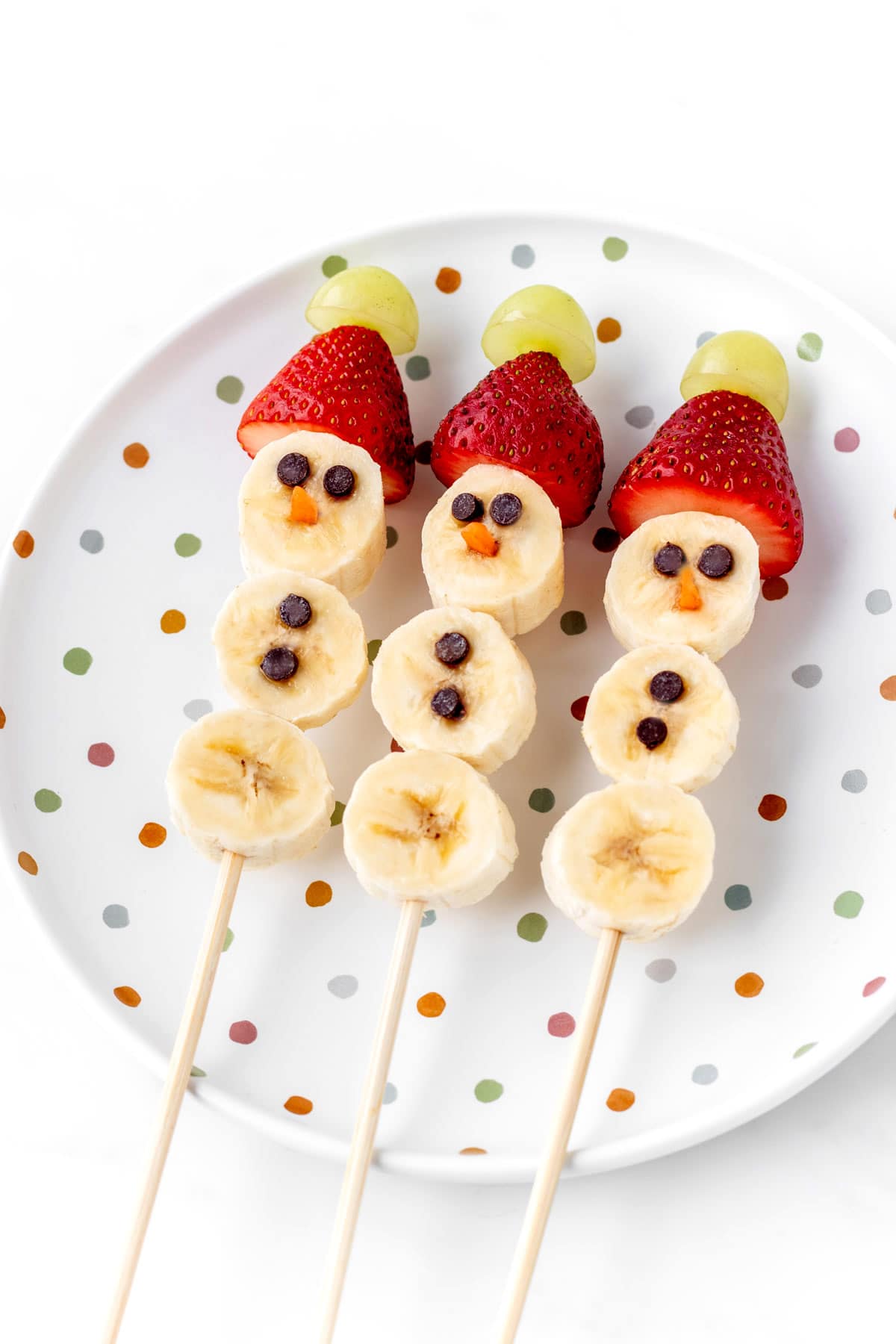 3 banana snowmen on a decorative, polka dot plate.