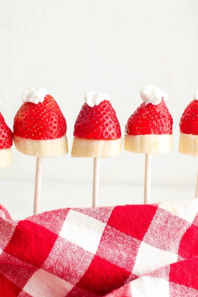 Strawberry Santa hats on sucker sticks, lined up.