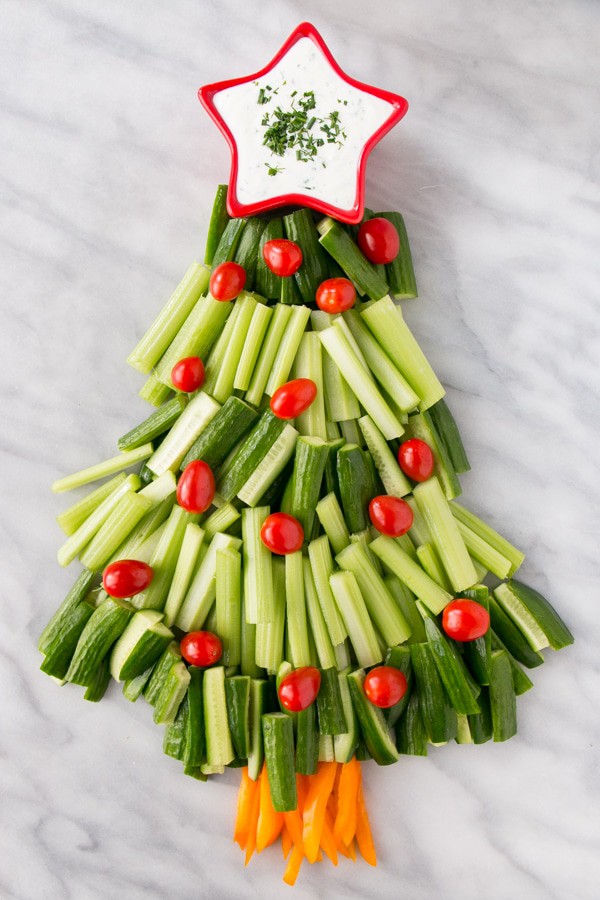 A Christmas tree veggie tray on a decorative tray with the dip in the shape of a star at the top.