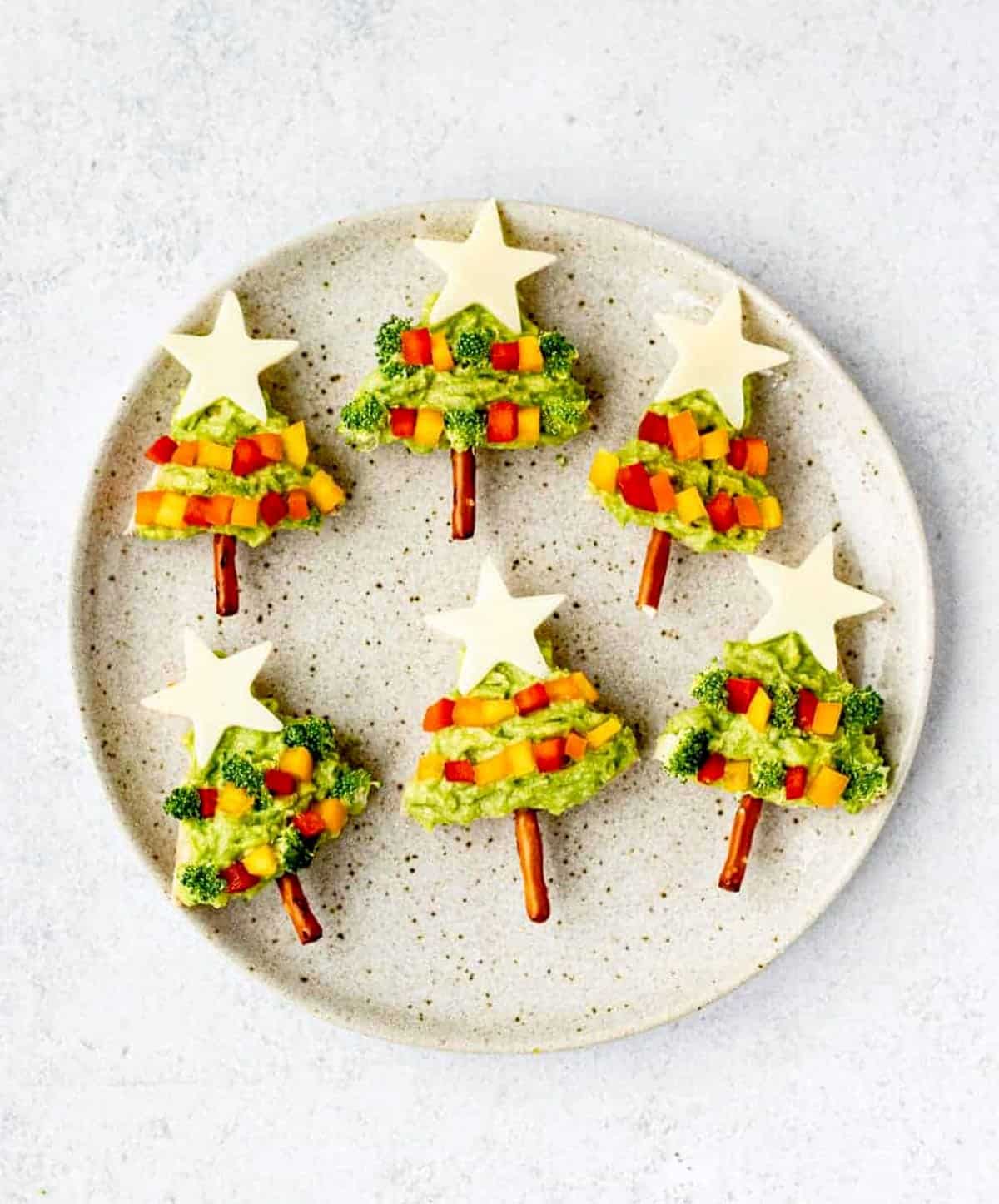 A birds-eye view of 6 avocado Christmas trees on a round, circular plate.