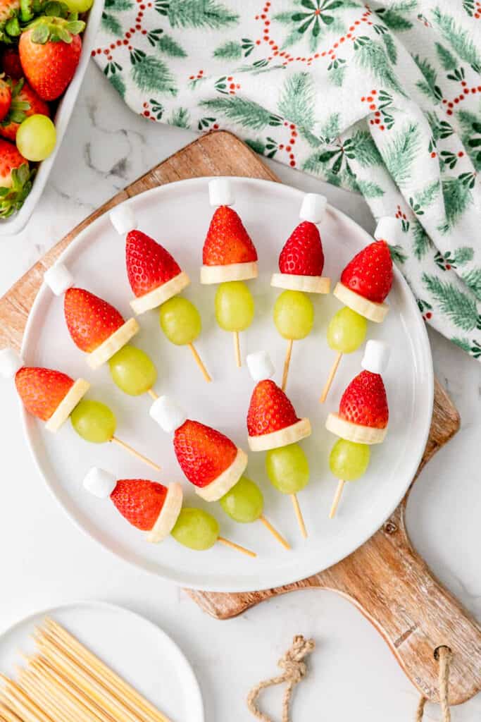 A white plate full of strawberry Santa hats.