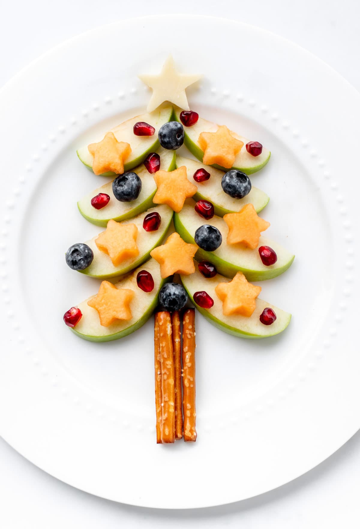 Close up of apple Christmas tree snack on a white plate.