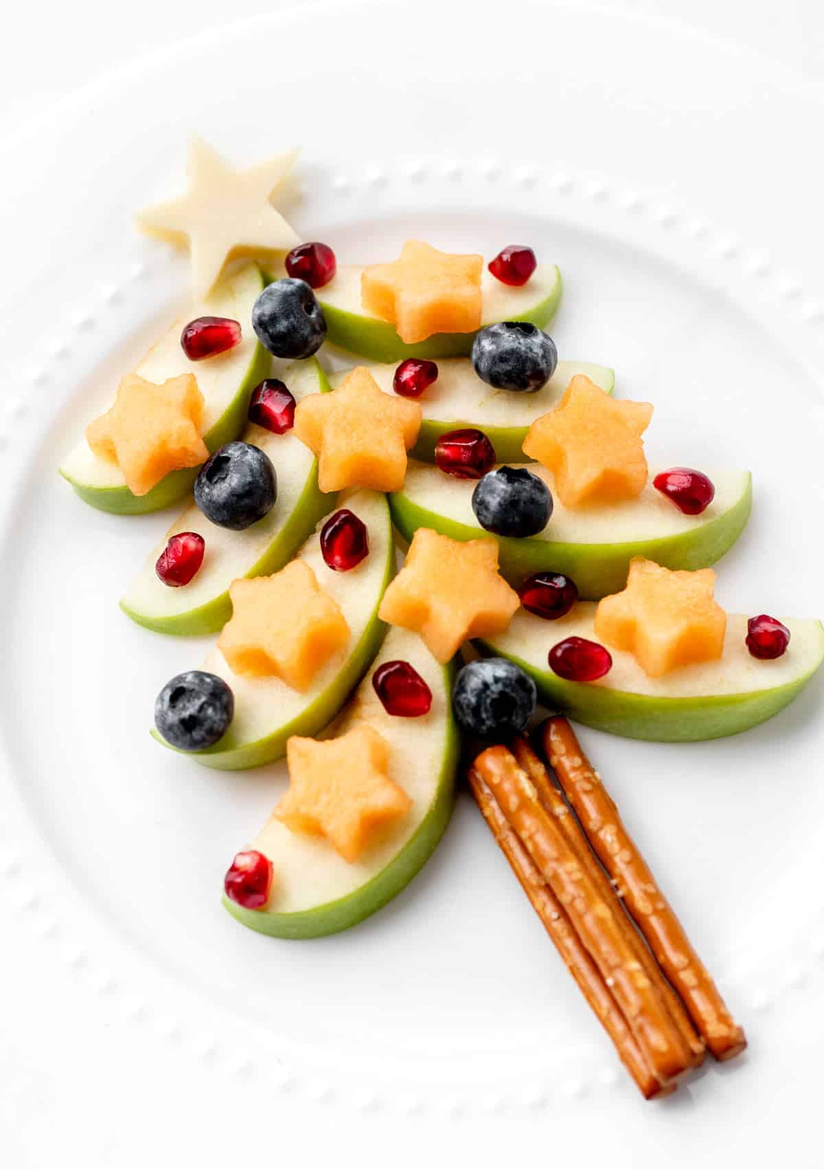 Green apple Christmas tree snack on a white plate.