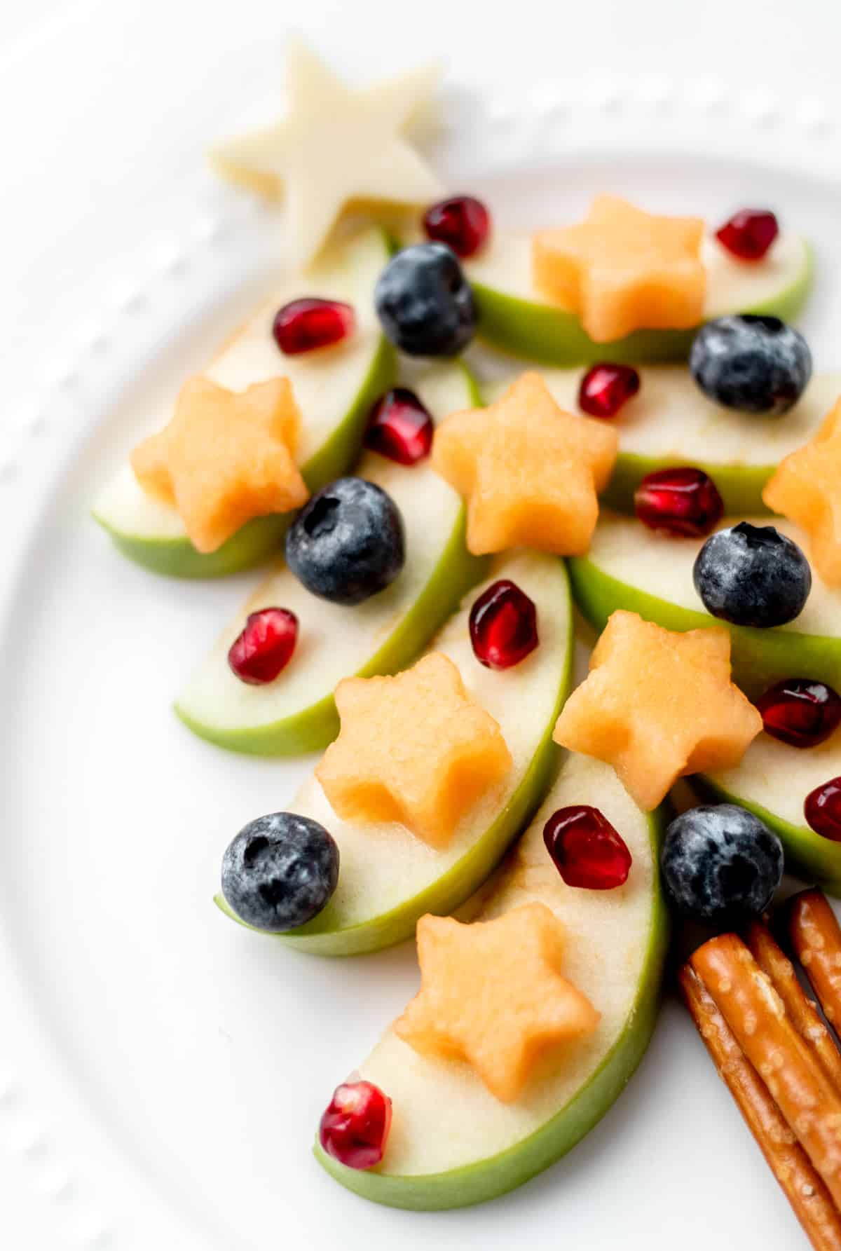 Close-up of green apple Christmas tree snack on a white plate.