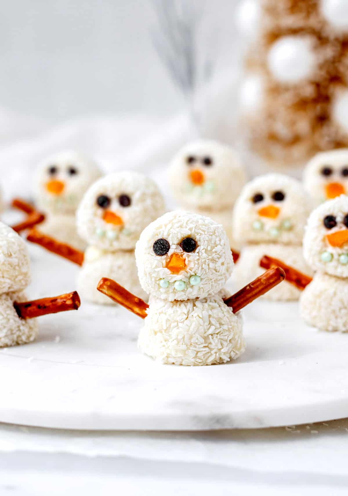 A close-up of snowman truffles on a decorative plate.