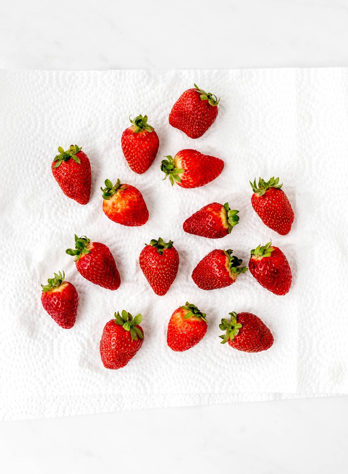 Freshly washed strawberries drying on a piece of paper towel.