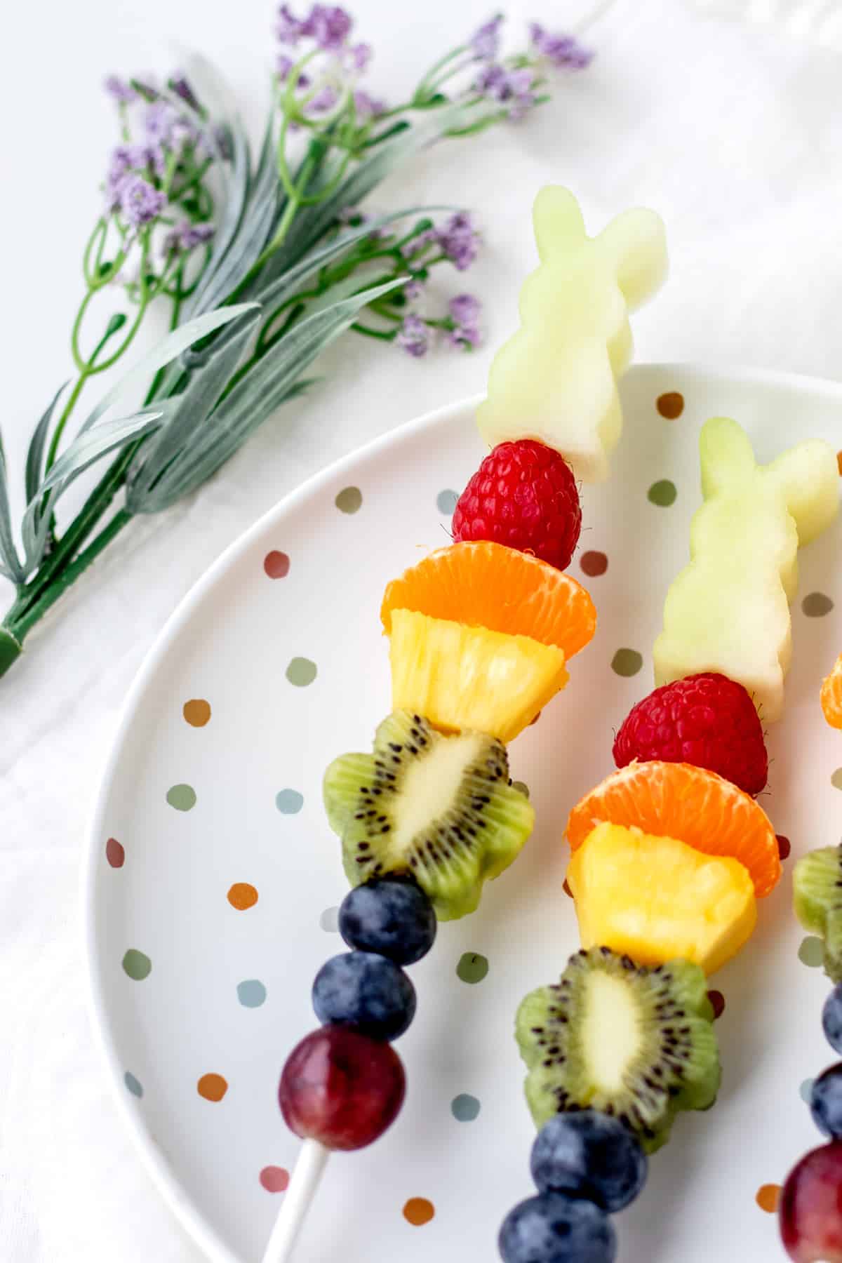 A close-up of Easter fruit kabobs on a polka-dotted plate.