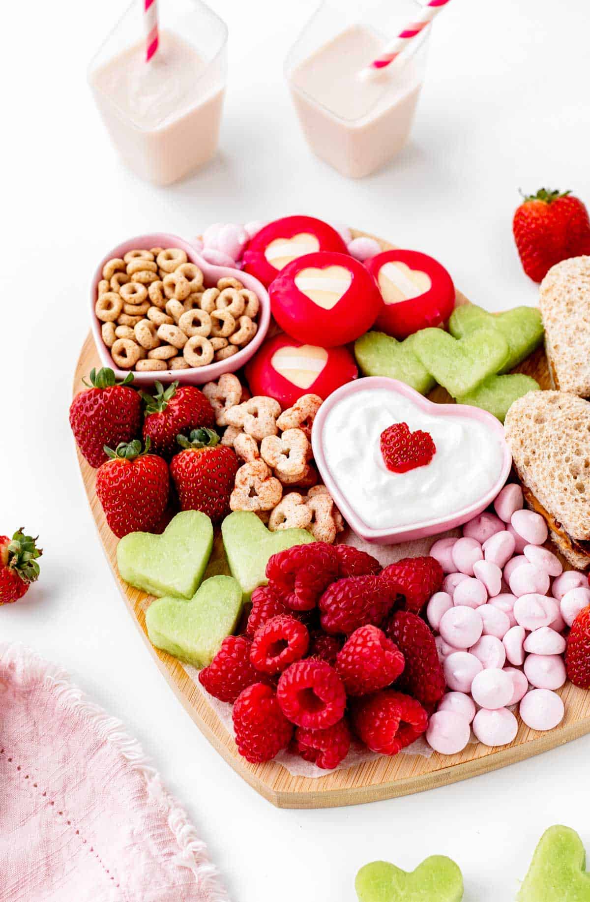 A close-up side view of the snacks on the heart shaped charcuterie board.