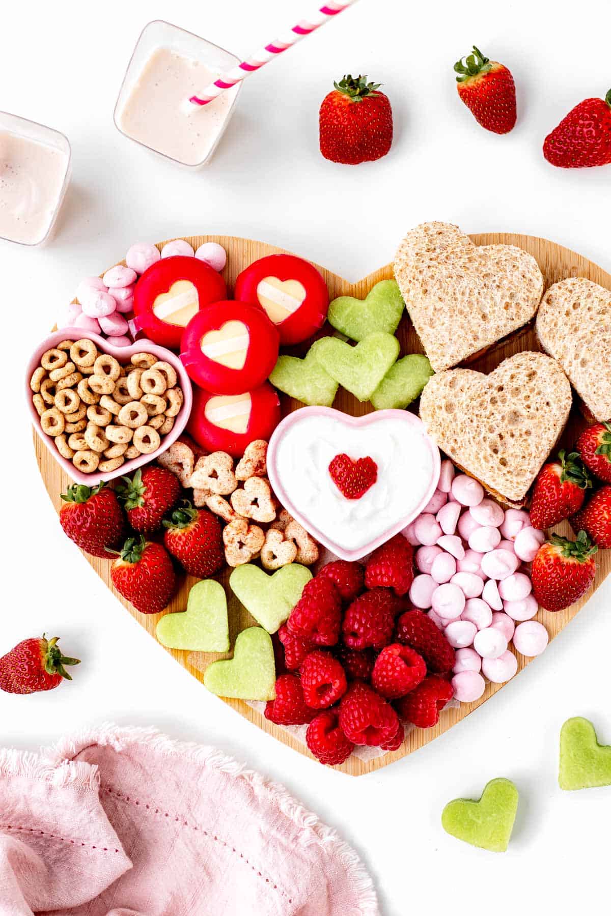 A heart shaped charcuterie board on a white counter.