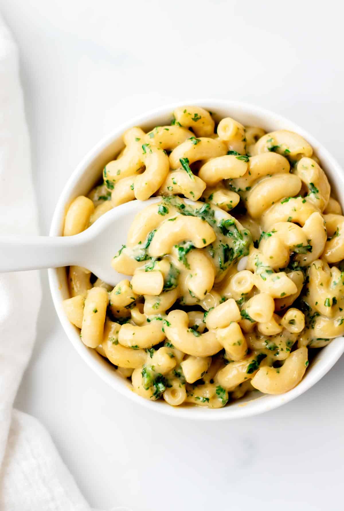 A birds-eye view of the kale mac and cheese in a white bowl.