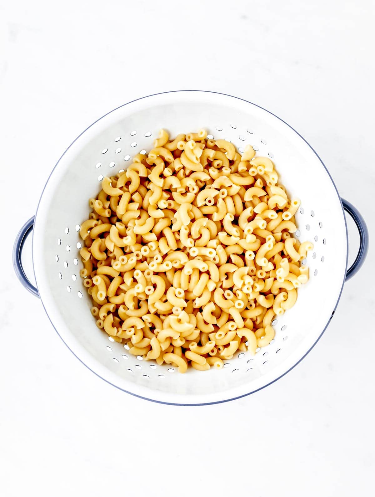 Cooked elbow pasta noodles in a strainer.