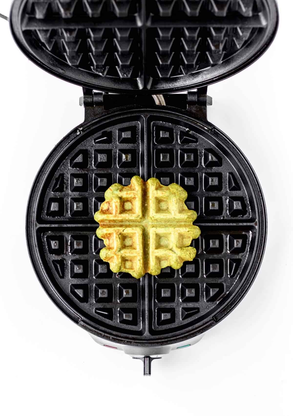 A cooked spinach banana waffle in a waffle iron.