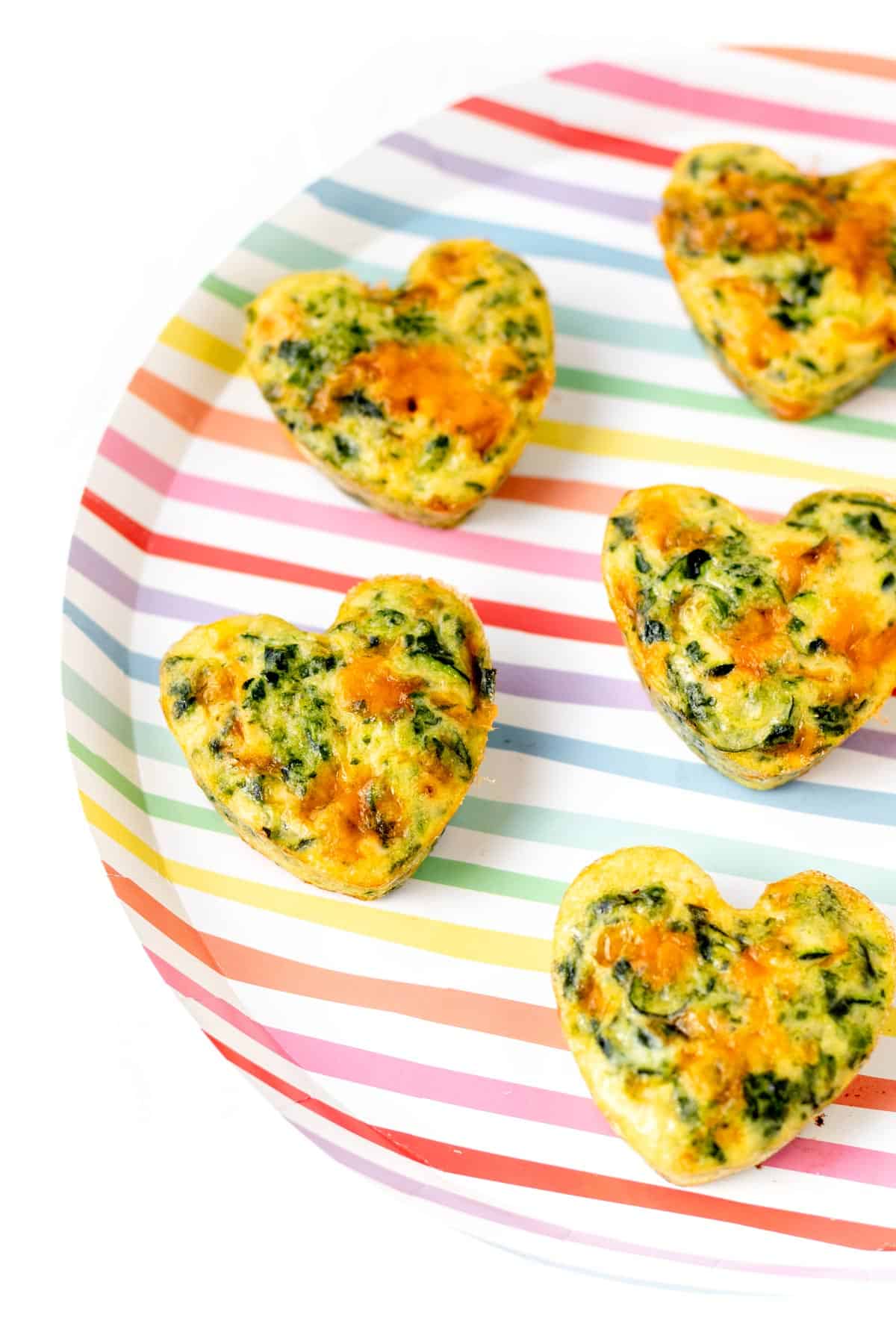 A few of the zucchini frittata muffins on a striped colorful plate.