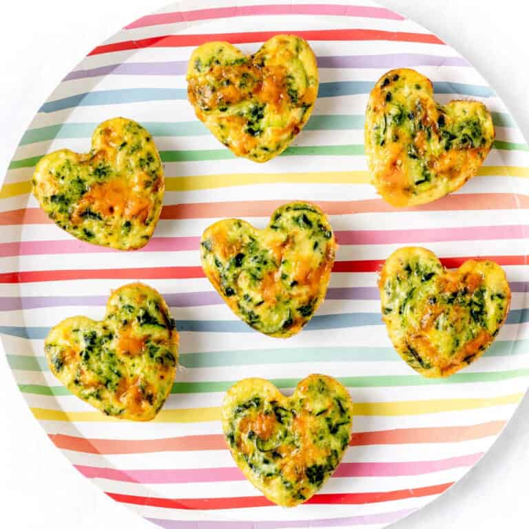 A striped plate full of heart shaped zucchini egg muffins.