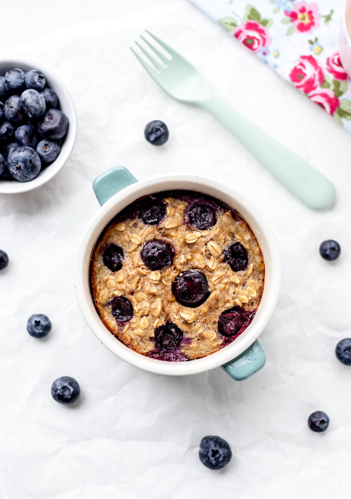 Baked oats for one in a small baking dish on a table next to a fork.