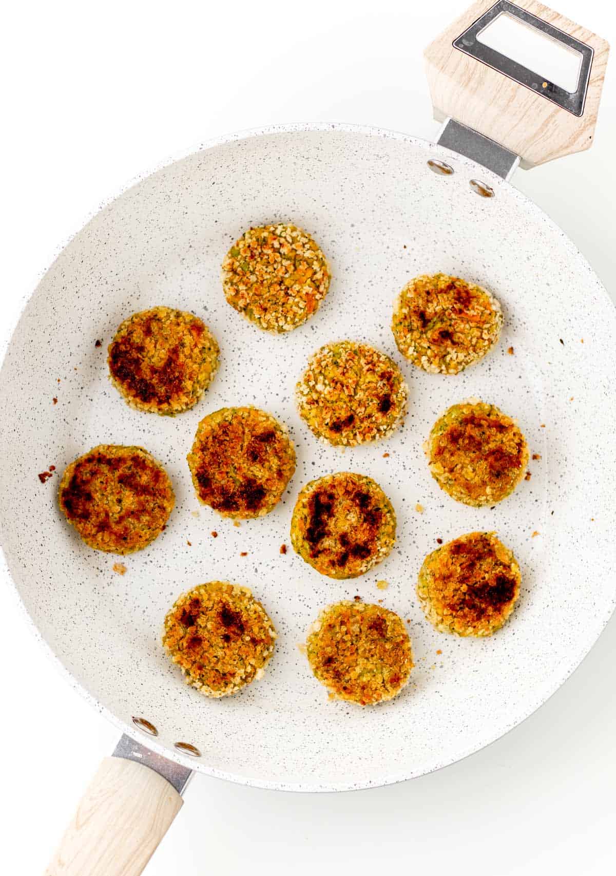 Cooking the chickpea veggie patties in a pan until crispy.