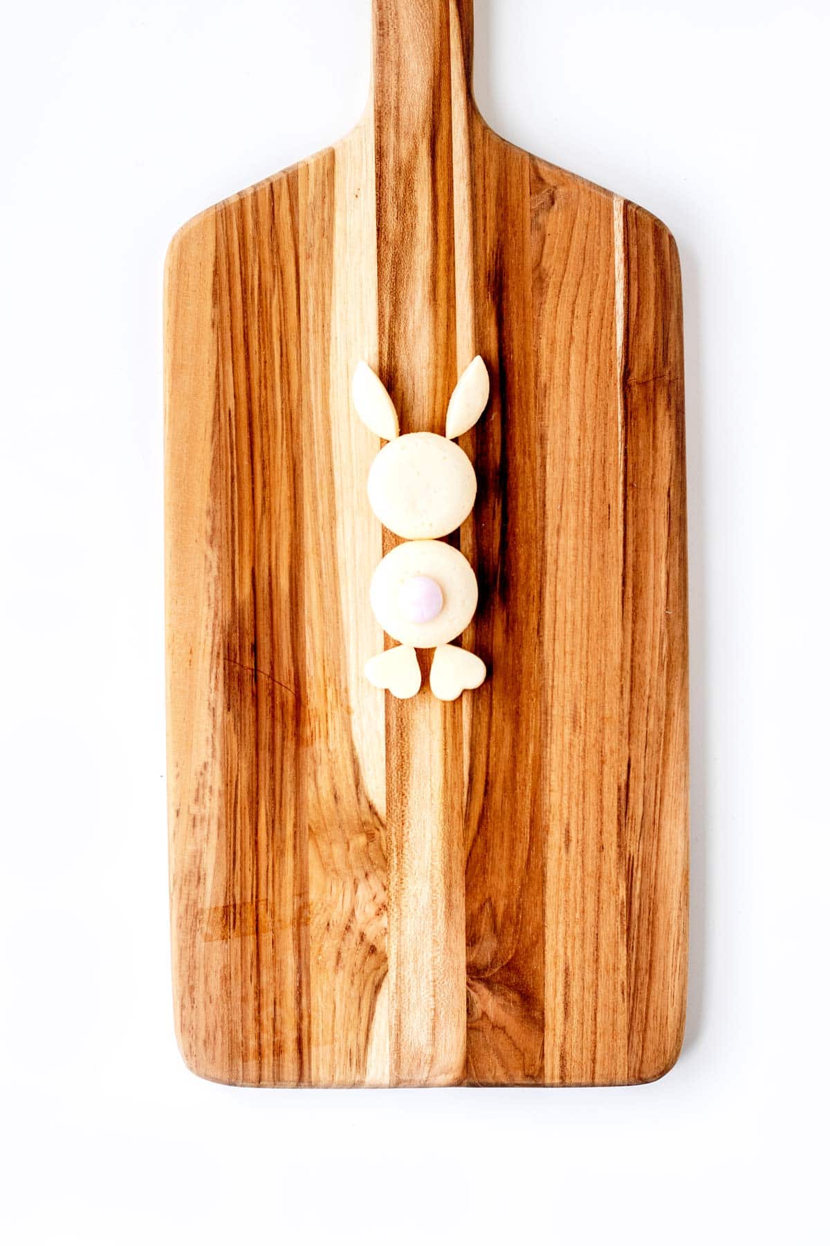 An Easter bunny made of baby bel cheese on a wooden cutting board.