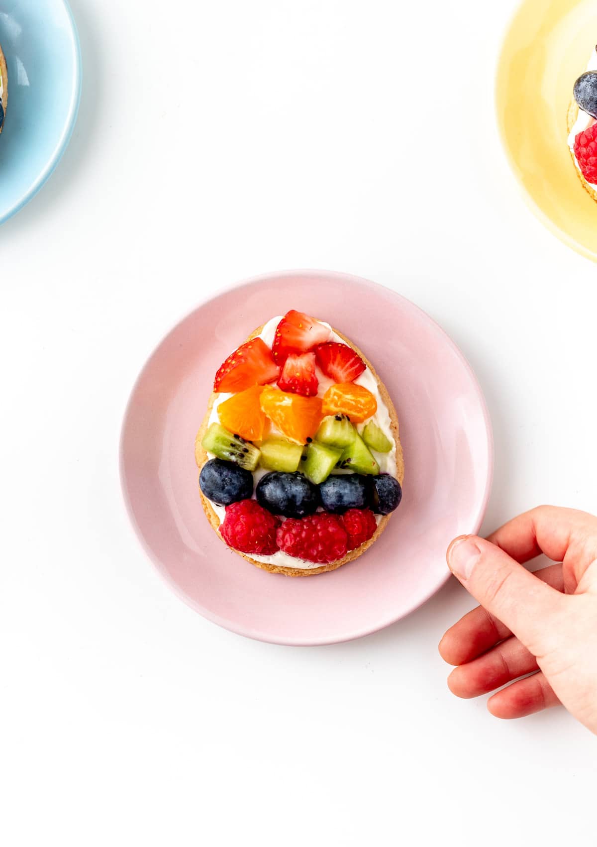 An Easter egg fruit pizza on a pink plate.