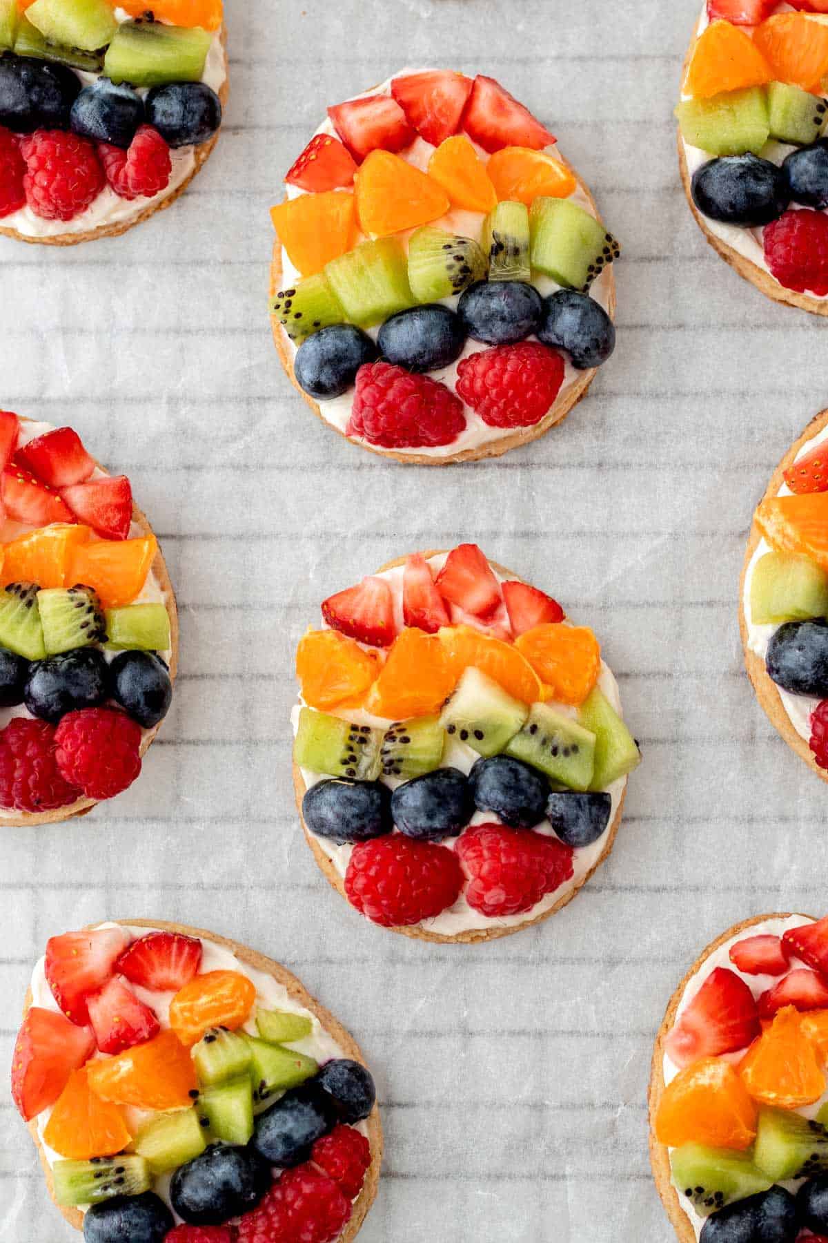 A close-up of fully decorated mini Easter egg fruit cookies on a cooling rack.