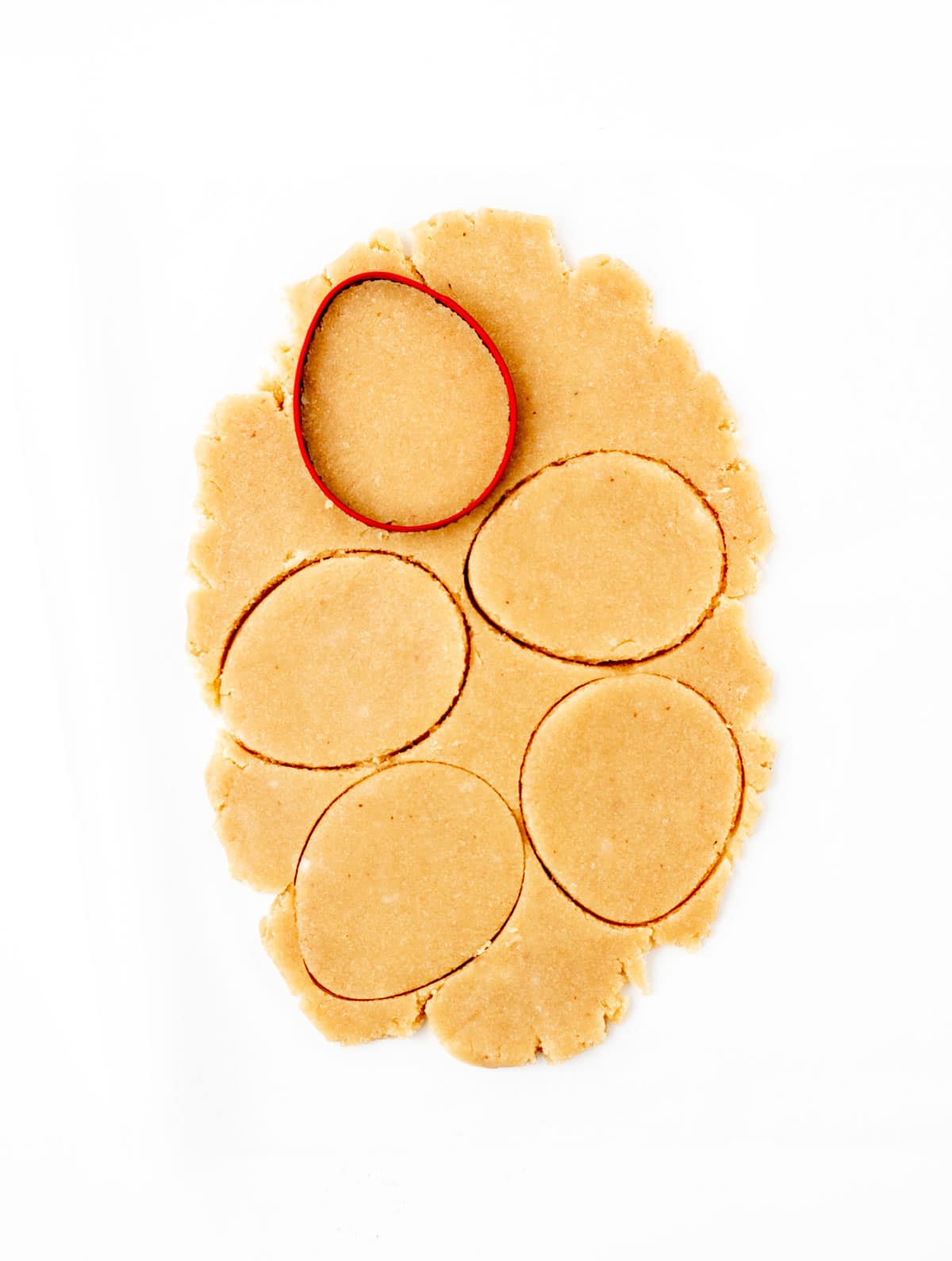 Making Easter egg shapes out of the dough with a cookie cutter.