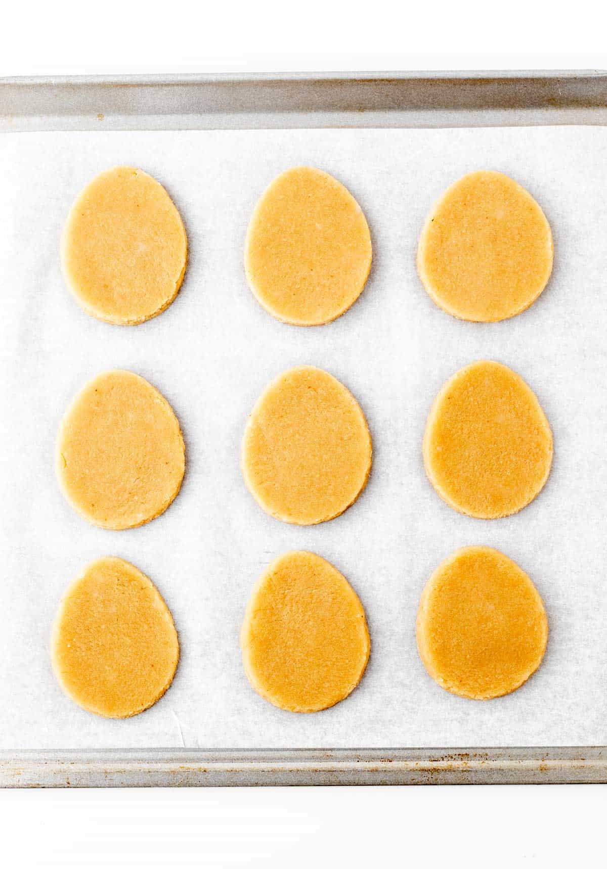 Easter egg shaped dough on a cookie sheet lined with parchment paper.