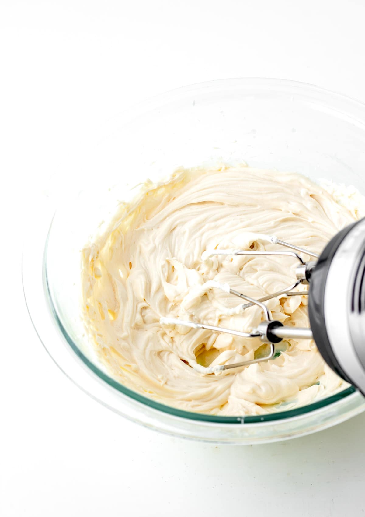 Mixing the fruit pizza frosting with a hand mixer.