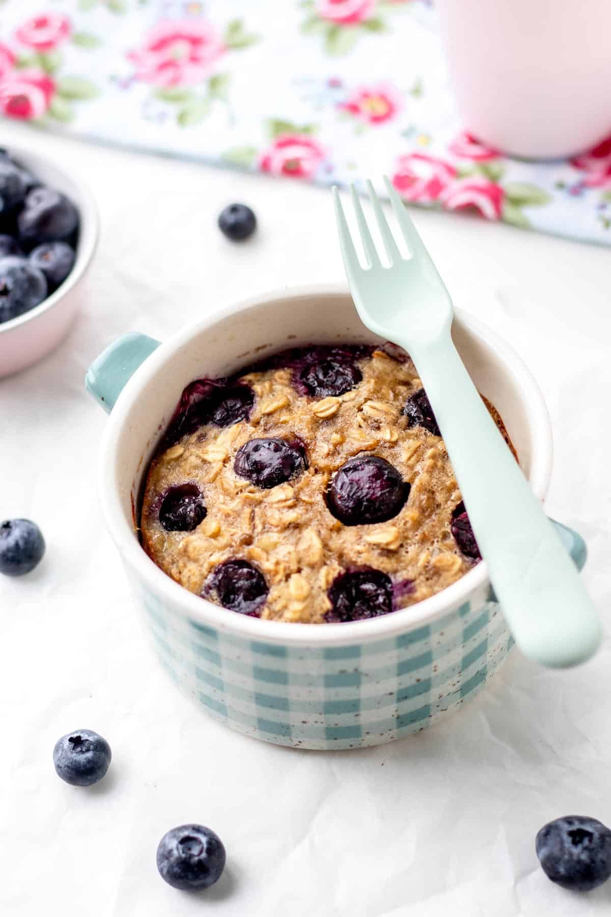 Healthy baked oats for one in a small blue and white plaid ramekin with a fork resting on top.