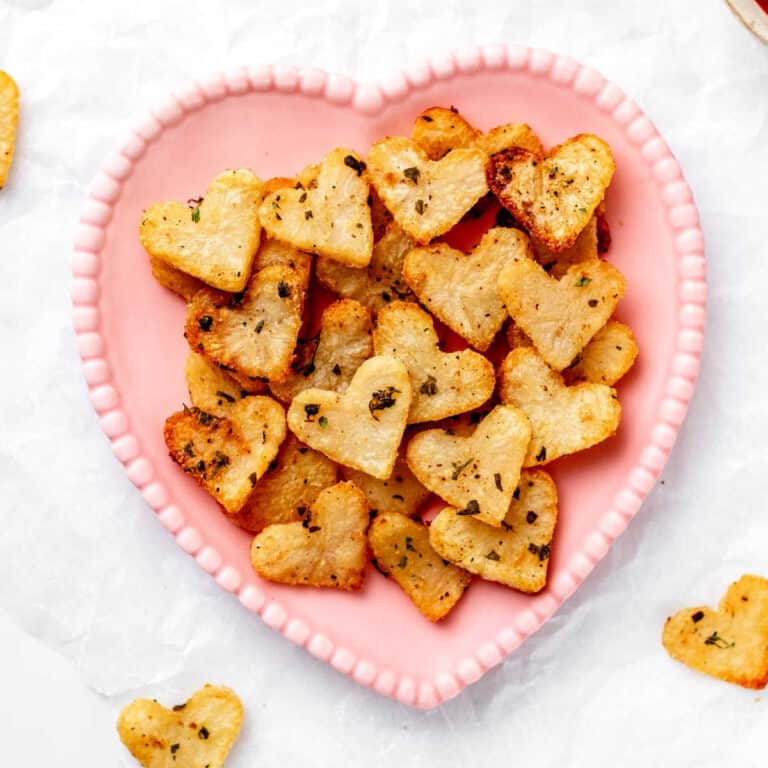 Roasted heart shaped potatoes on a pink heart-shaped plate.