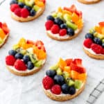 Decorated Easter fruit pizzas lined up on a cooling wrack.