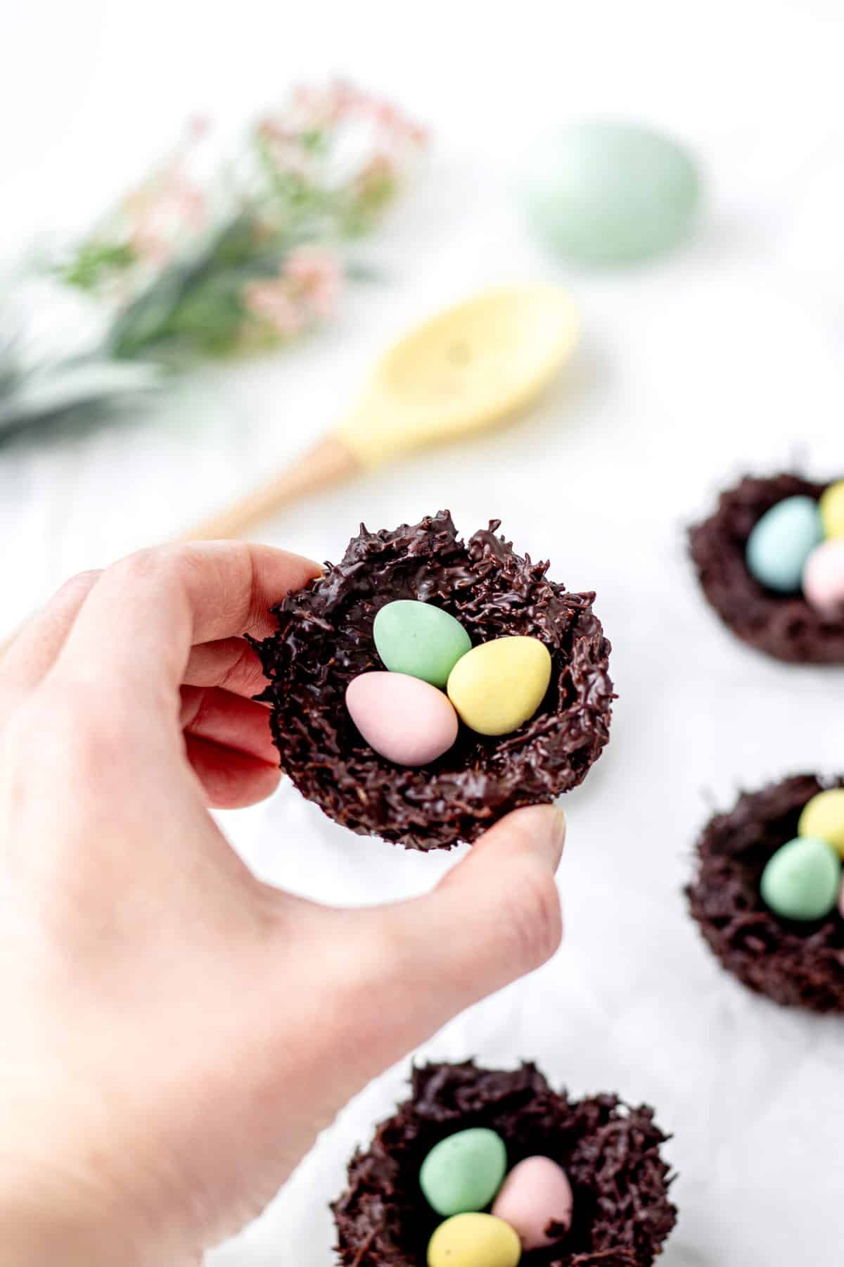 Someone holding a shredded wheat Easter nest in between their fingers.