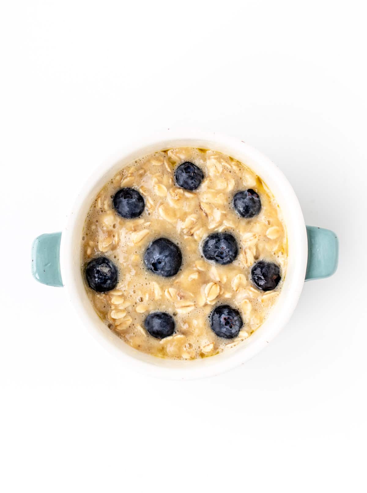 Blueberries poked into the baked oatmeal mixture in a ramekin.