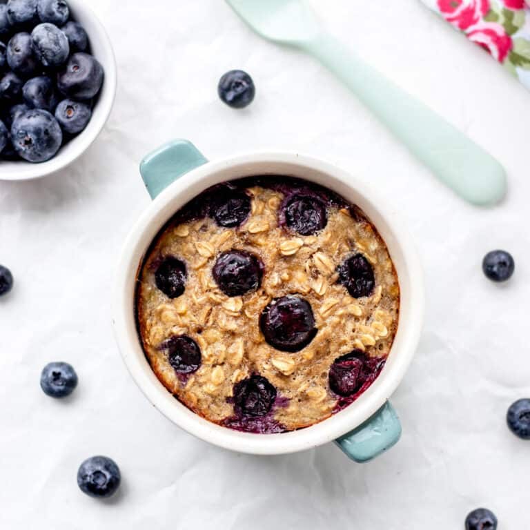 Single serving baked oatmeal in a ramekin with blueberries and a fork.