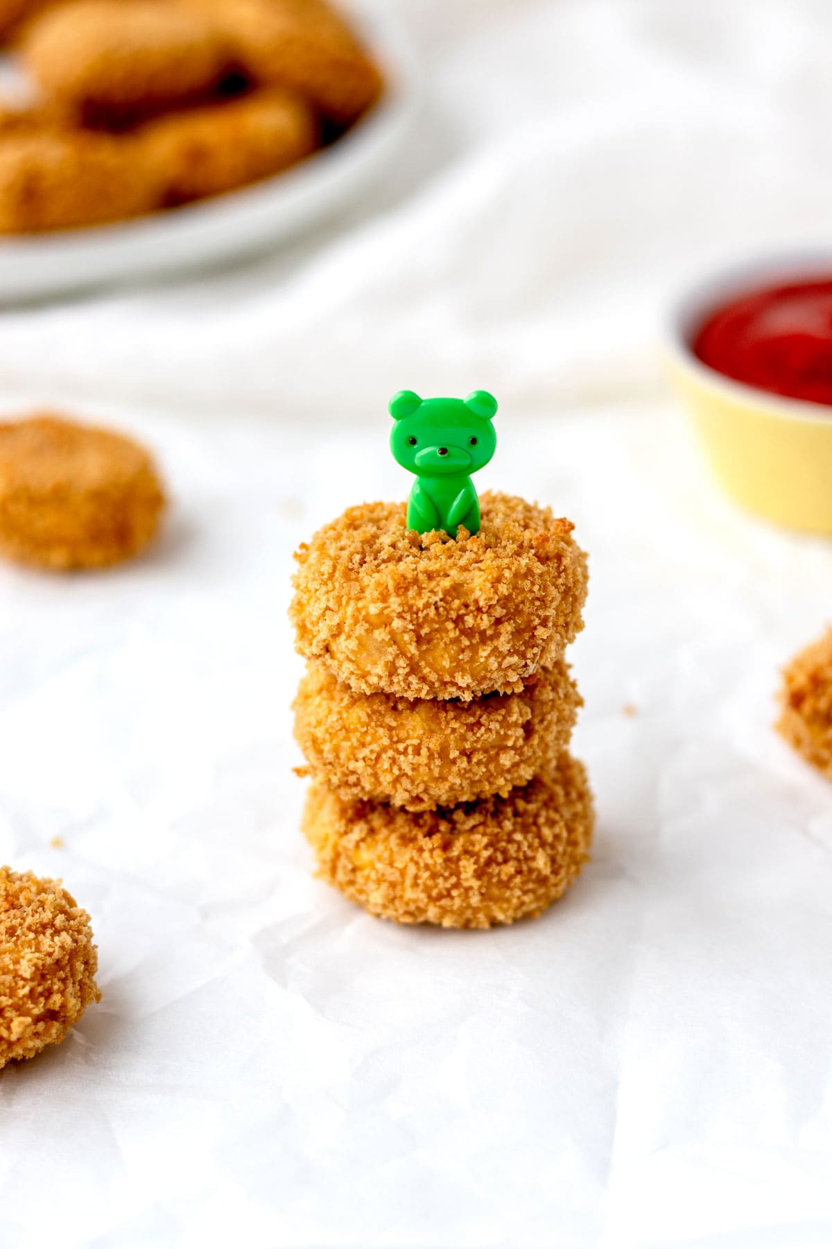 Cauliflower chicken nuggets stacked on top of each other with a little bear toothpick sticking in the top.
