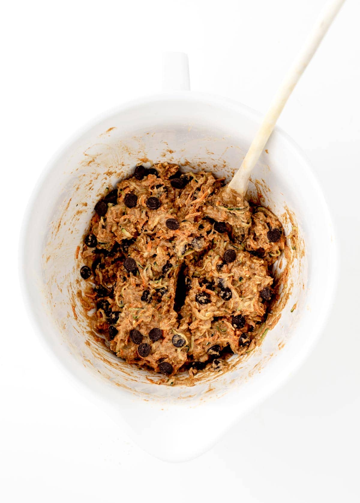 Combining the chocolate chips in with the hidden veggie cookie dough in a mixing bowl with a wooden spoon.