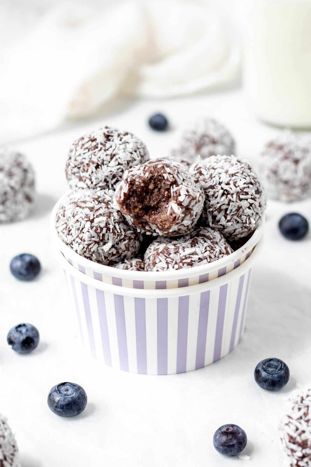 Blueberry bliss balls stacked on top of one another in a small white bowl.