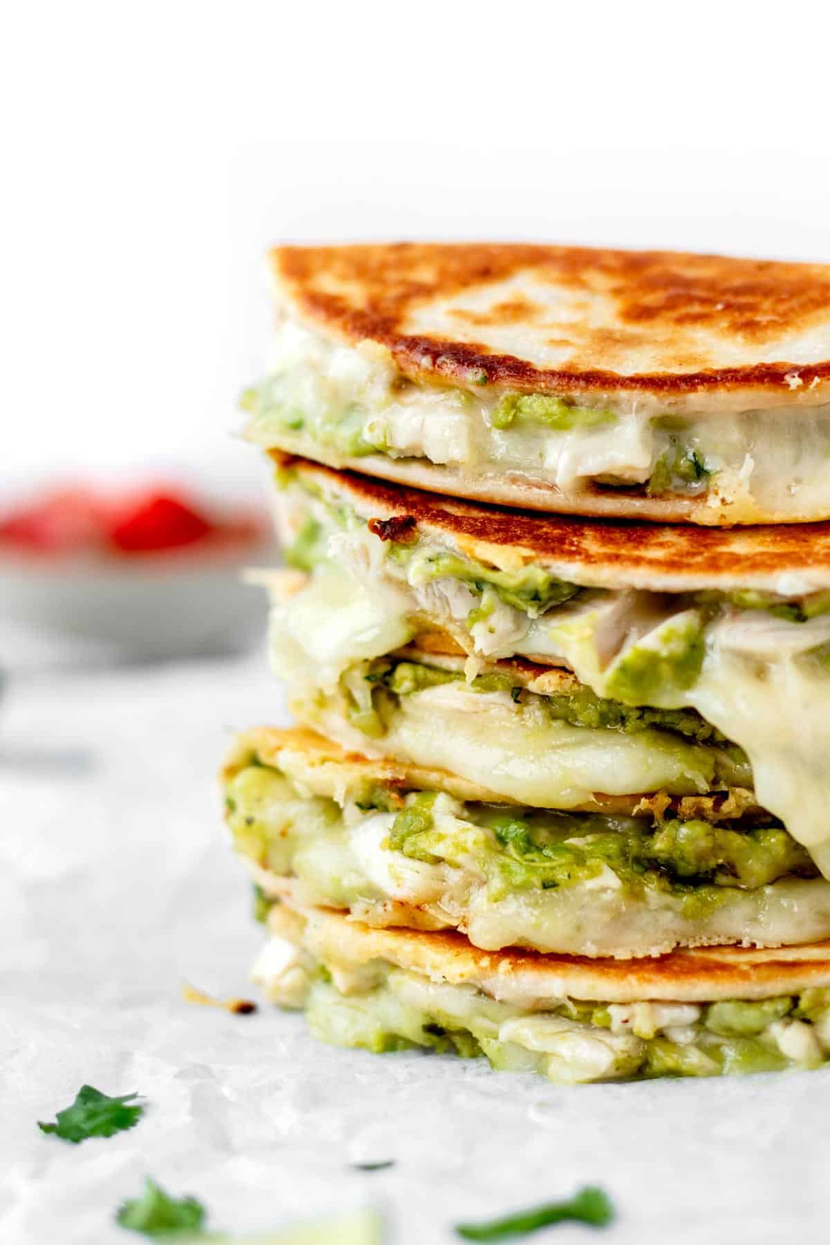 A stack of mini chicken quesadillas with the cheese oozing out of them.