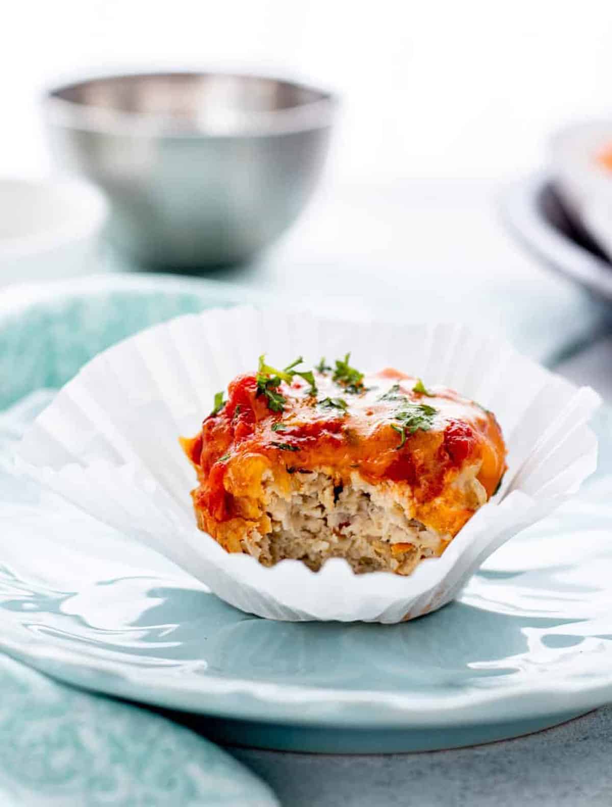 A chicken muffin in a muffin liner on a plate.