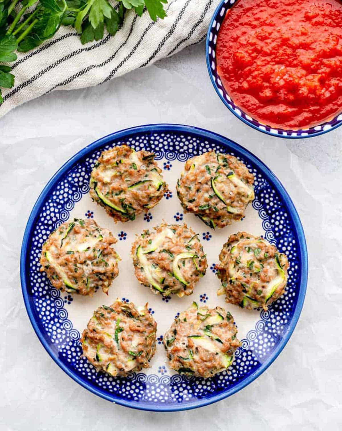 A decorative plate full of chicken zucchini poppers on a table.