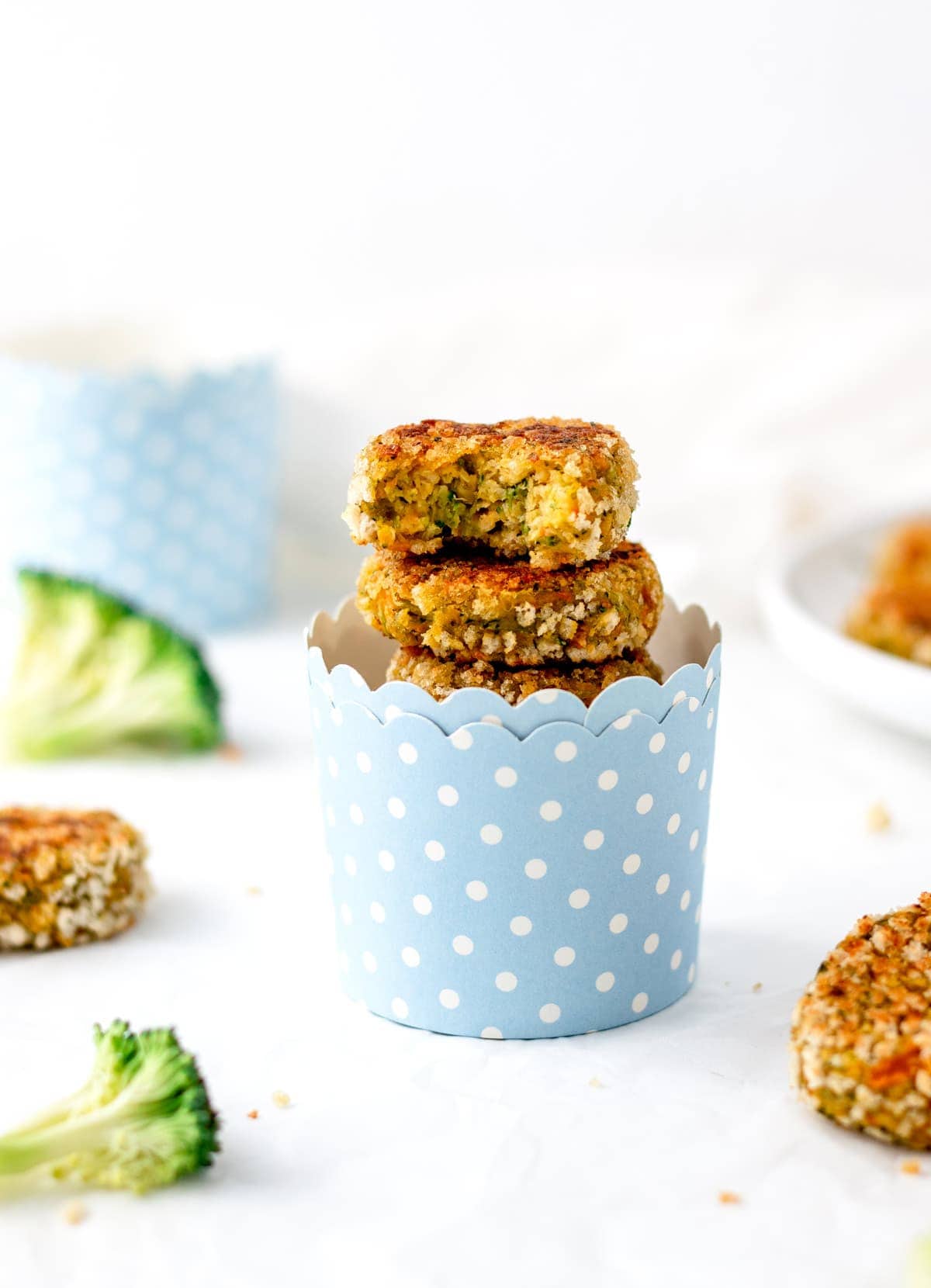 Homemade chickpea veggie patties stacked on top of one another in a blue and white polka dot cup.